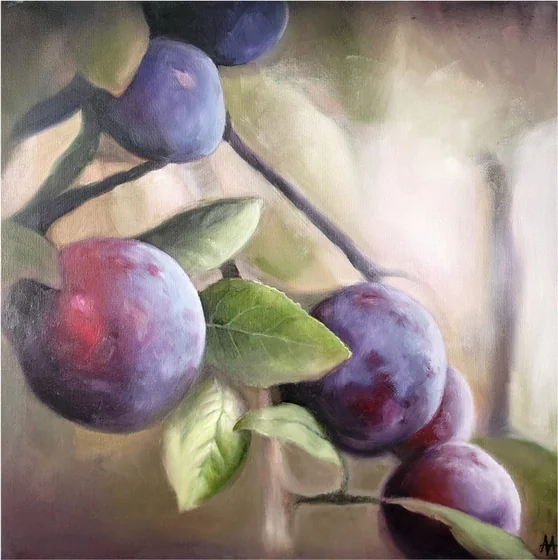 Plums hanging on a branch with green leaves